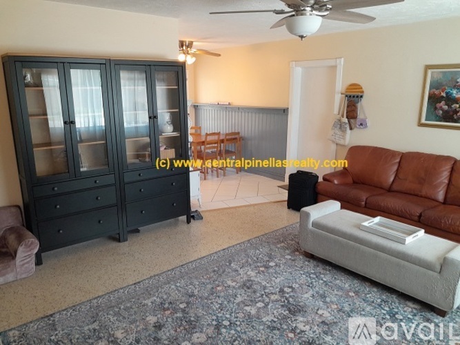 A living room with a brown leather couch and a black cabinet.