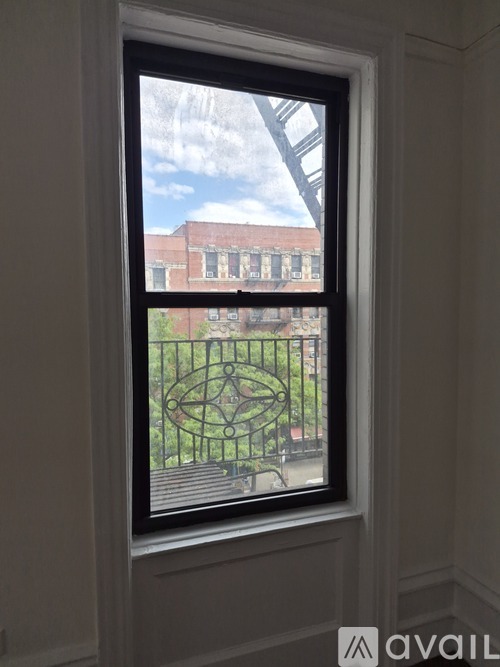 A window with a view of a green lawn and a red building.