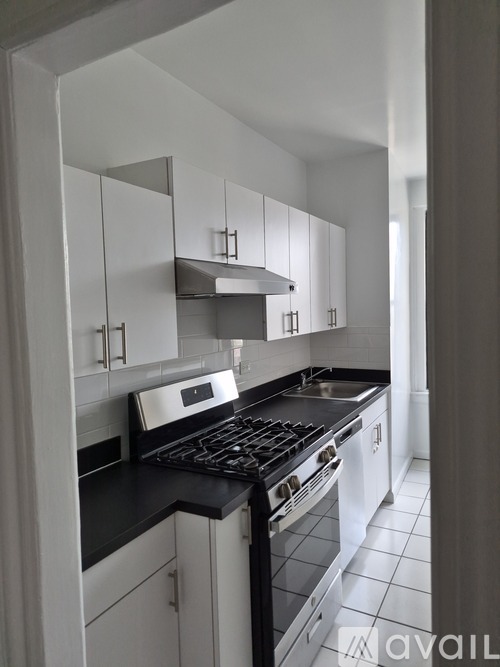 A kitchen with white cabinets and black countertops.