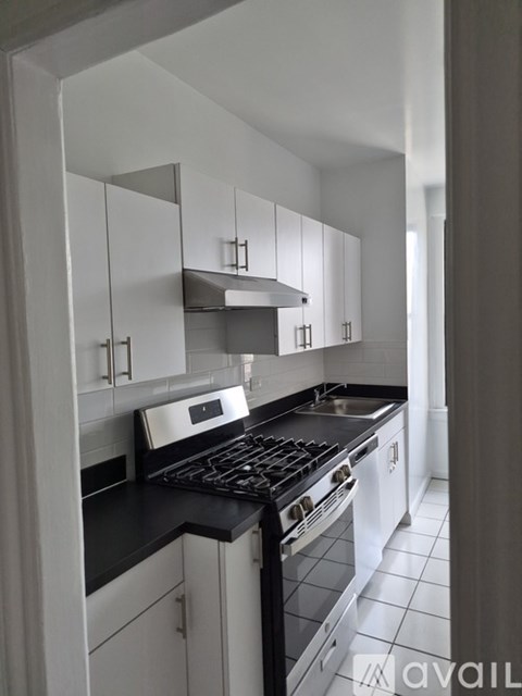 A kitchen with white cabinets and black countertops.