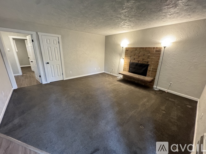 A room with a fireplace and a grey carpet.