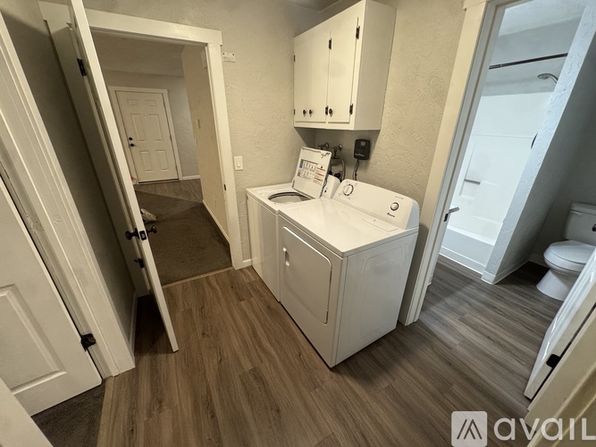 A small white cabinet with a toiletries box on top is in a room with a toilet and a sink.