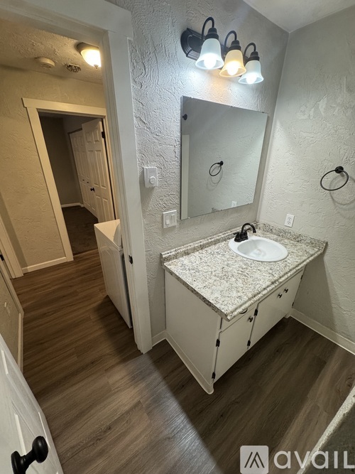 A bathroom with a sink, mirror, and light fixture.
