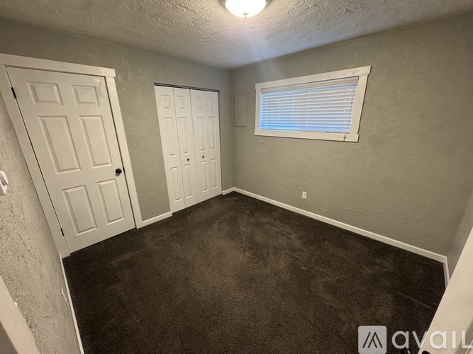 A room with two doors and a window with blinds.