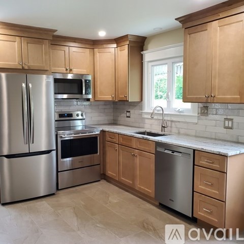 A kitchen with wooden cabinets and a stainless steel refrigerator.