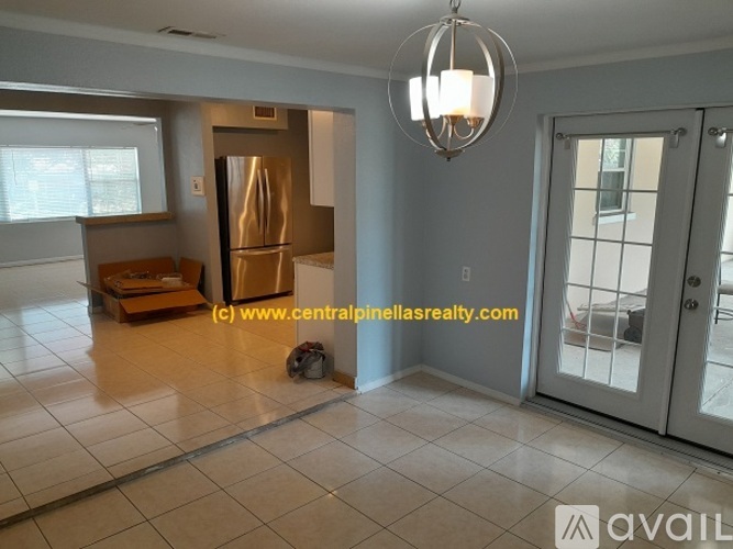 A spacious living room with a refrigerator, a sofa, and a chandelier.