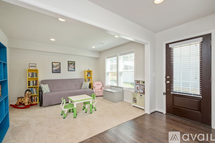 A living room with a grey couch, a green coffee table, and a bookshelf with books and toys.