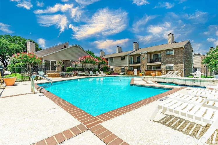 A swimming pool surrounded by a brick border and lounge chairs.