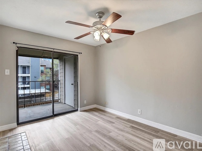 A room with a ceiling fan and sliding glass doors leading to a balcony.