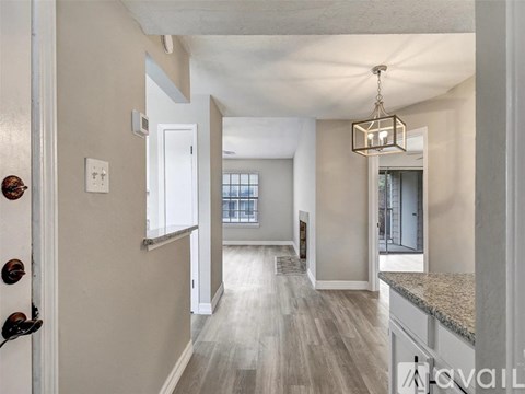 A well-lit, spacious hallway with a door on the left and a kitchen area on the right.