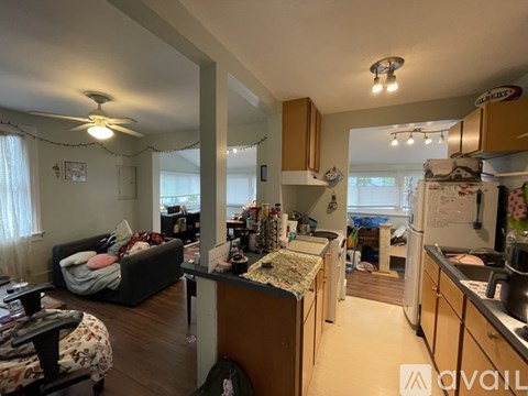 A living room with a couch and a kitchen area with a refrigerator.
