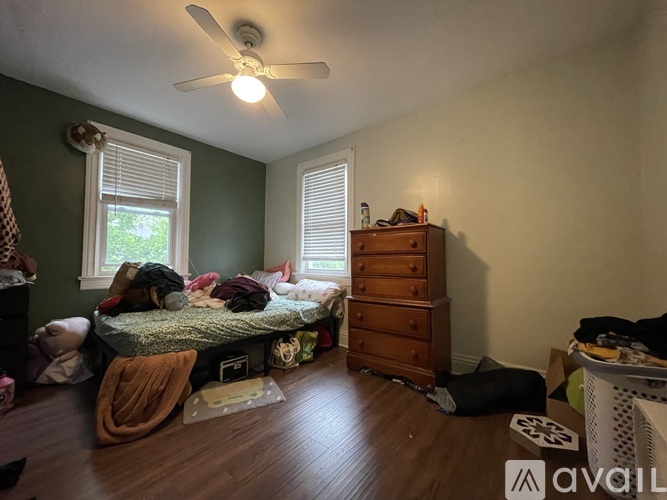 A room with a bed, dresser, and a ceiling fan.