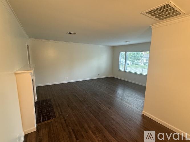 A room with wooden flooring and a window letting in natural light.