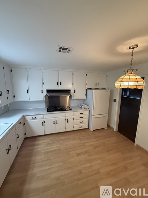 A kitchen with white cabinets and a wooden floor.