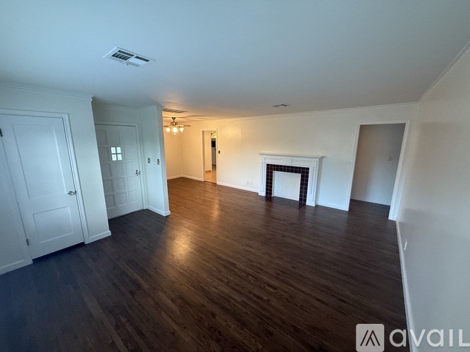 A spacious room with wooden floors and white walls.