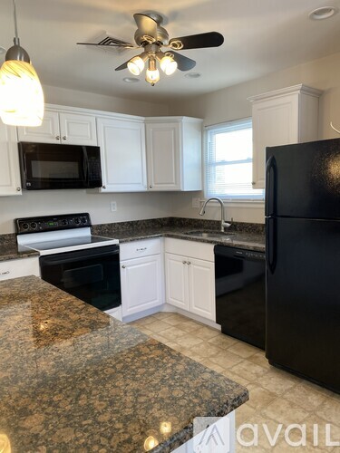 A kitchen with granite countertops and a black refrigerator.