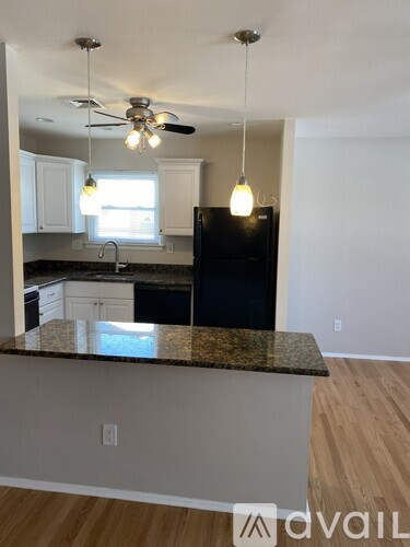 A kitchen with a black fridge and a ceiling fan.