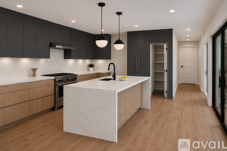 A modern kitchen with a marble island and dark cabinets.