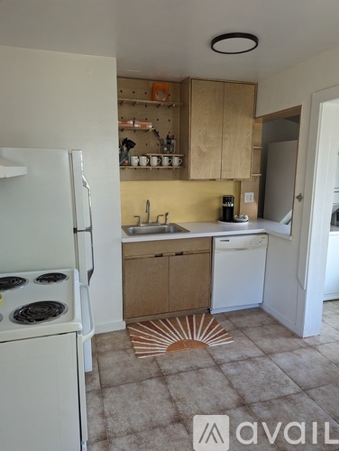 A kitchen with a white fridge, a white dishwasher, and wooden cabinets.