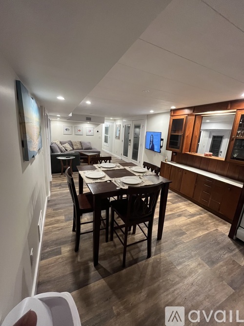 A dining room with a table set for four and a television mounted on the wall.