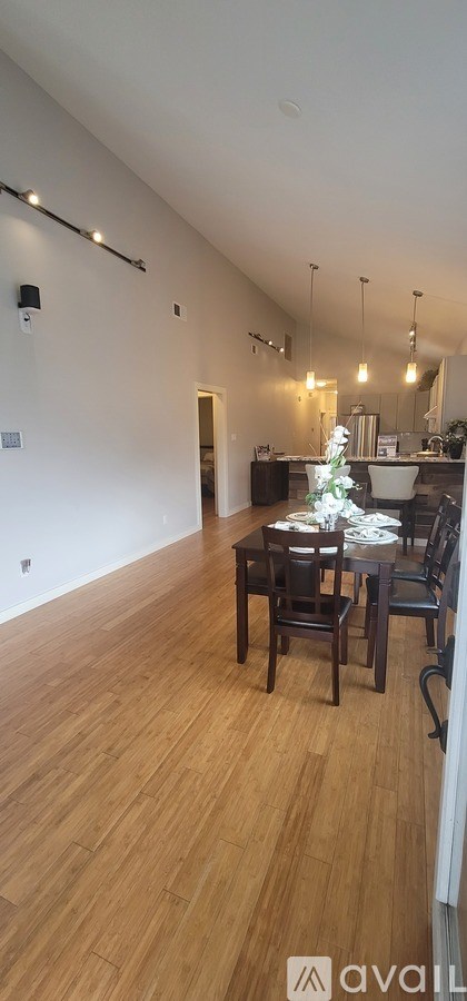 A room with wooden flooring and a dining table set up.