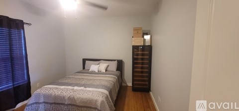 A bedroom with a bed, a dresser, and a window with blinds.