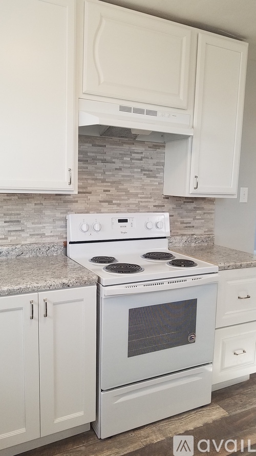 A white stove and oven in a kitchen with white cabinets.
