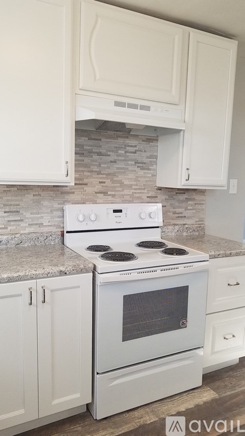 A white stove and oven in a kitchen with white cabinets.