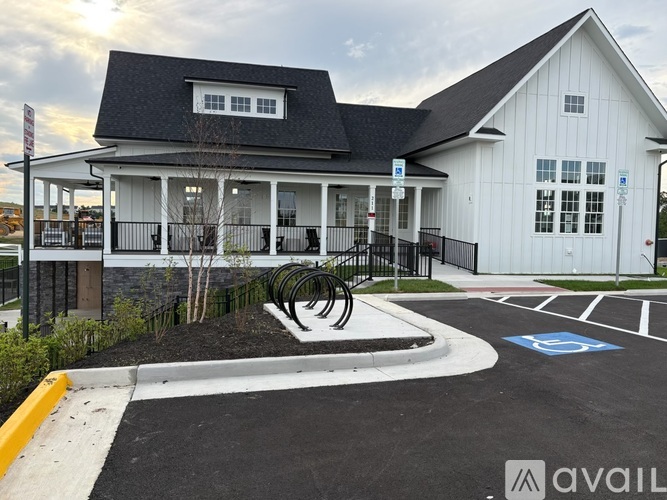 A white building with a black roof and a parking lot in front.