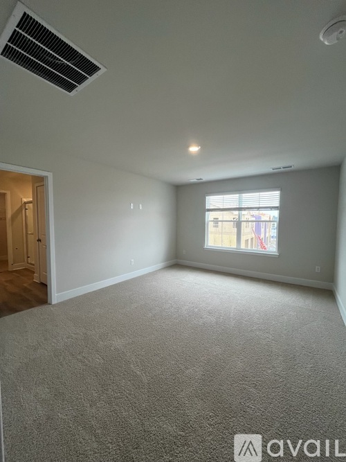 A spacious room with a window and carpeted floor.