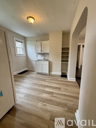 A kitchen area with wooden flooring and white cabinets.