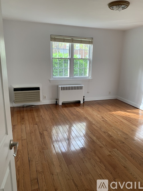 A room with wooden floors and a window with blinds.