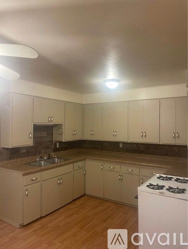 A kitchen with a white stove and cabinets.
