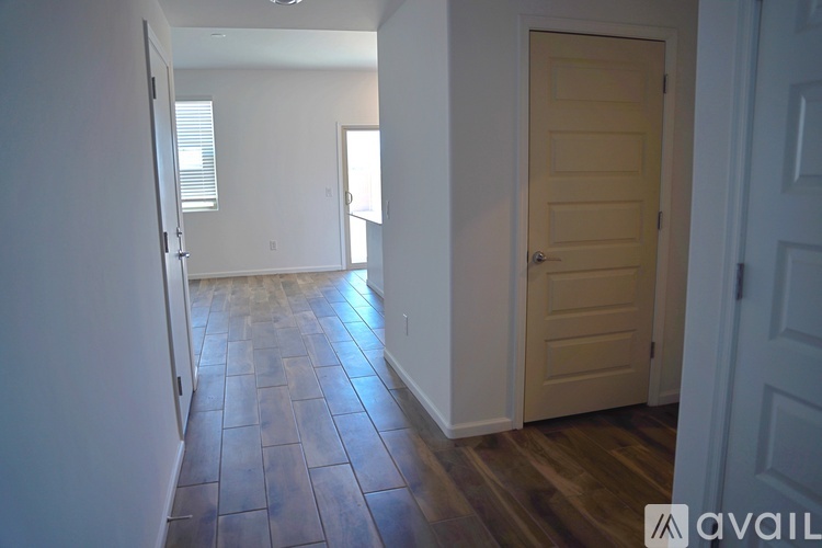 A hallway with a wooden floor and a white door.