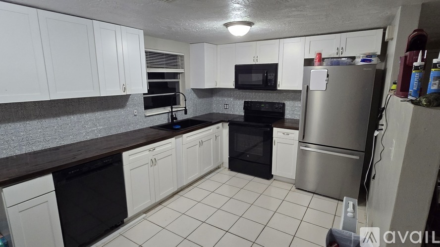 A kitchen with white cabinets and a black dishwasher.