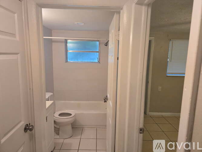 A bathroom with a toilet, tub, and window.