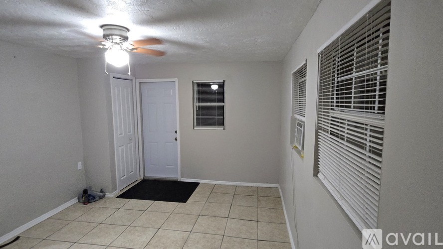 A room with a ceiling fan, a door, and a window with blinds.