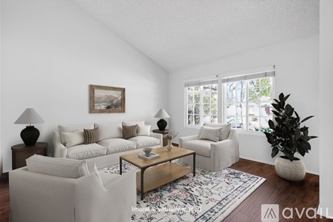 A living room with a white couch, a coffee table, and a painting on the wall.