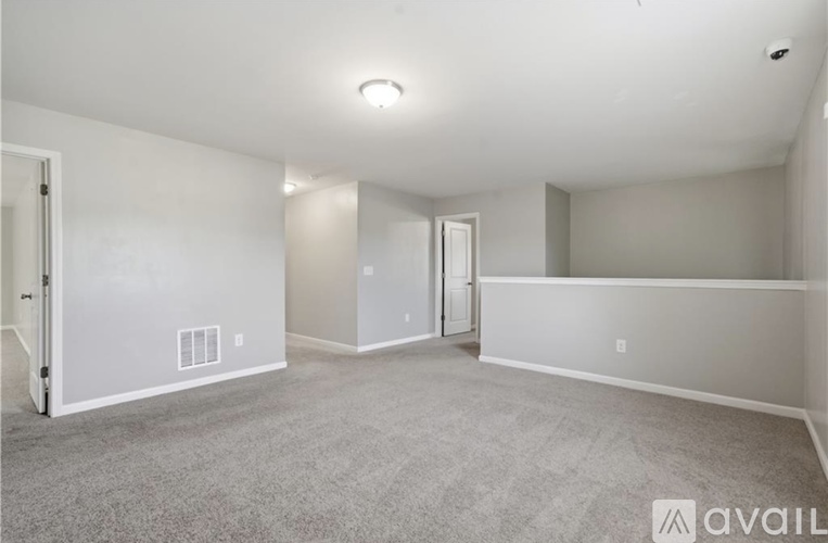 A spacious room with a carpeted floor and white walls.