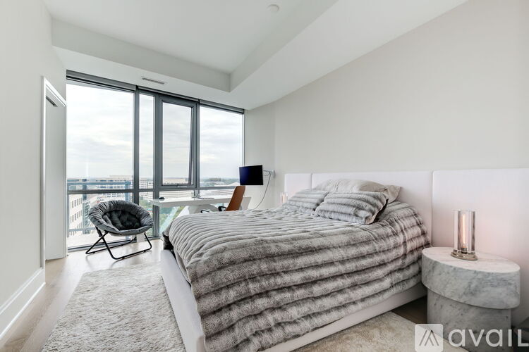 A bedroom with a large bed and a chair by the window.