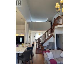 A well-lit, spacious living room with a staircase leading to the upper floor.