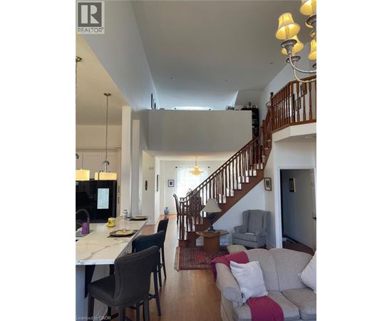 A well-lit, spacious living room with a staircase leading to the upper floor.