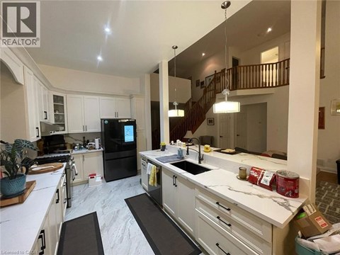 A kitchen with white cabinets and a black fridge.