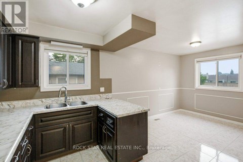 A kitchen with brown cabinets and a marble countertop.