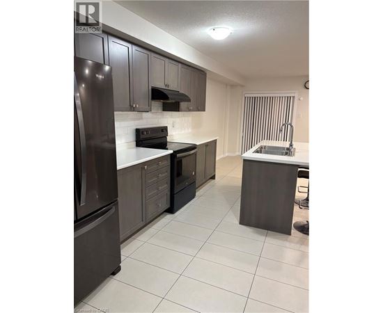 A kitchen with a refrigerator, oven, and sink.