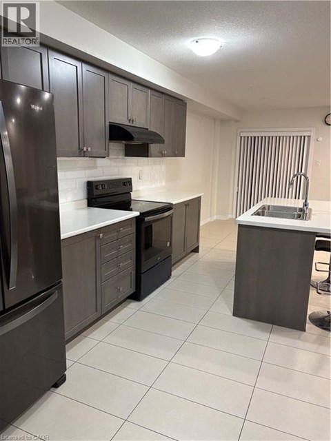 A kitchen with a refrigerator, oven, and sink.