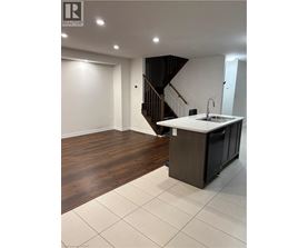 A modern kitchen with a wooden floor and white walls.