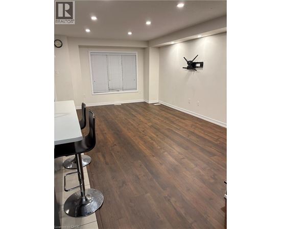A room with wooden flooring and a white table with two chairs.