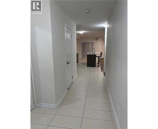 A long white hallway with a door on the left and a desk with a chair on the right.