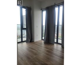 A room with wooden floors and large windows with curtains.